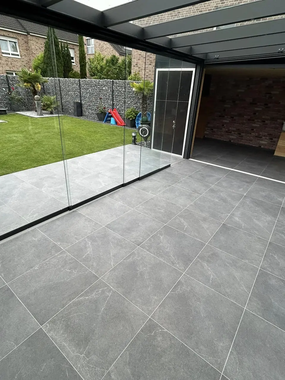 Überdachte Terrasse mit großformatigen Feinsteinzeugplatten