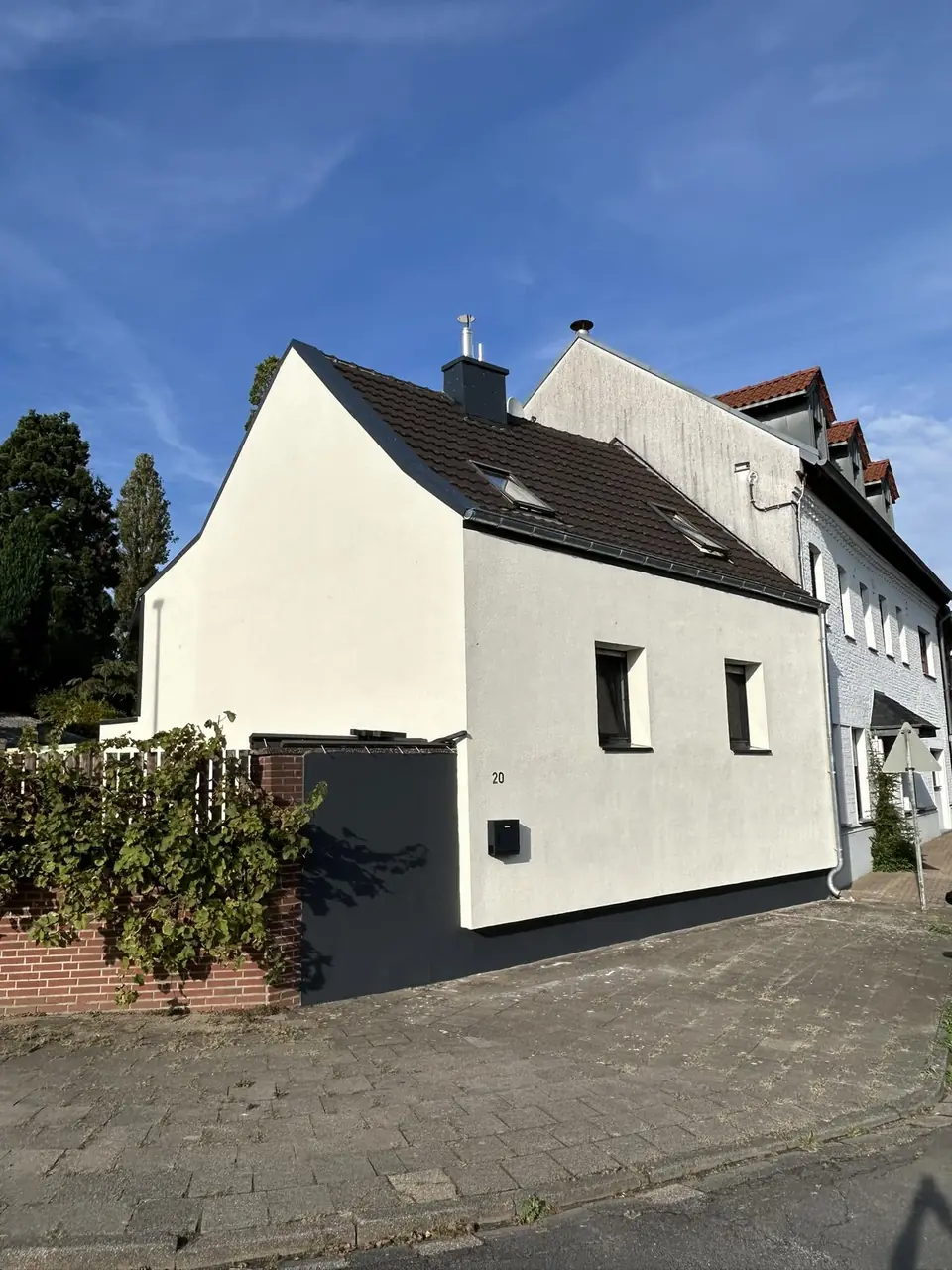 Einfamilienhaus mit heller Putzfassade und dunklem Sockel