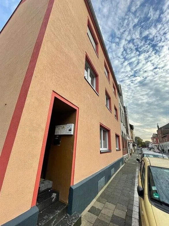 Sanierte Putzfassade mit roten Faschen am Hauseingang